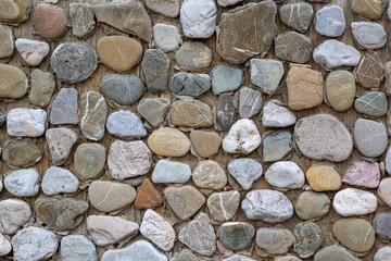 Stone wall made of pebbles, background, texture, backdrop