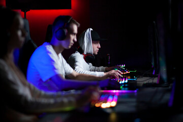 people play a computer in a computer club, a gamer guy in headphones is focused on the game, team play