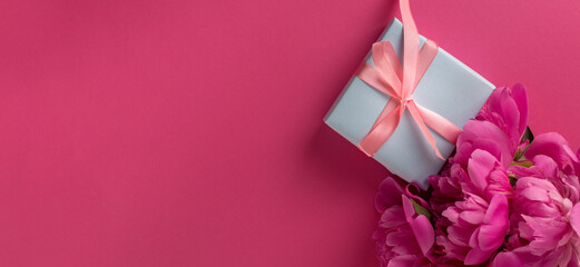 Valentine's Day Background with Pink Peonies and Gift Box With Satin Pink Bow on a Magenta Color Background.