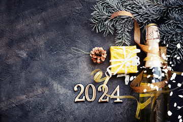 happy new year 2024 card with bottle of champagne and present gift over dark stone background