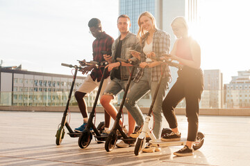 interracial group of friends rent electric scooters with telephones, multiracial youth connect with smartphones to eco transport, eco transport rental concept