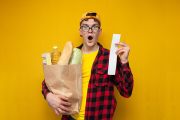 rising prices for groceries, guy buyer holds package of groceries and is surprised at the high prices, shocked shopper