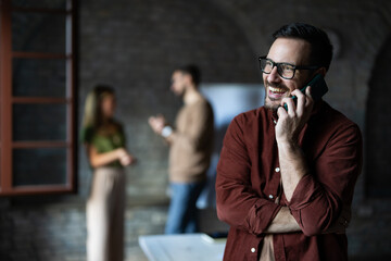 Smiling handsome businessman talking on the phone at business conference