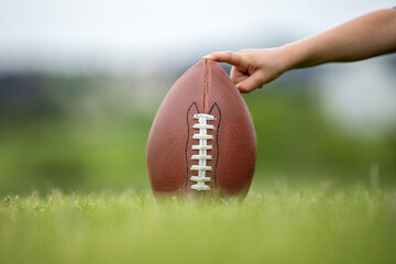 Child holder holding football for a kick by the placekicker laces towards viewer