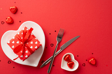 Saint Valentine's Day concept. Top view photo of heart shaped dish with present box cutlery...