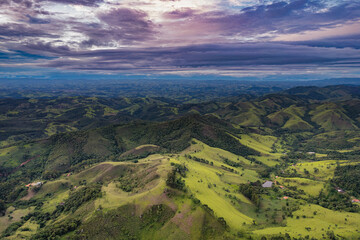 Aerial view of countryside landscape. Clouds with shades of purple, orange and green vegetation. Dramatic sky.