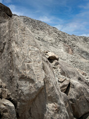 figura humanoide tallada en roca, petroglifos  primitivos en Huancor, Perú con cielo azul © Prock86