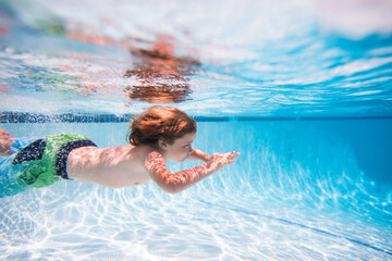 Kid swimming underwater in pool. Summer vacation. Blue sea water. Child boy swimming in sea.
