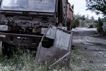 Fototapeta na wymiar Broken old truck that has been badly damaged abandoned in the middle of a park in the midday