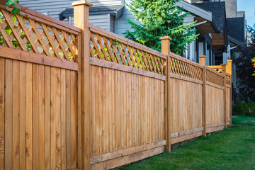 Nice wooden fence around house. Wooden fence with green lawn. Street photo - Powered by Adobe