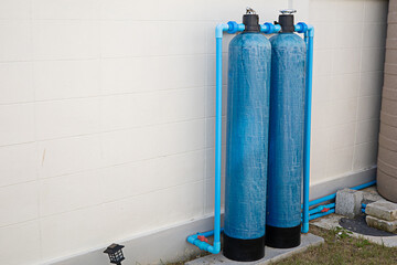 The water filter tank is installed on the wall of the fence of the house.