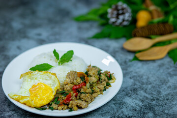 Rice topping stir fried basil with minced pork and fried egg thai food spicy prepare serving hot on the table dark marble is my dinner.