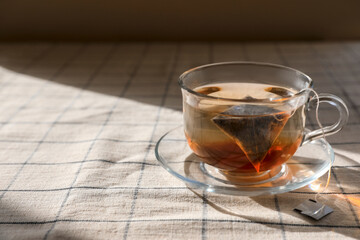 Tea bag in glass cup on table. Space for text