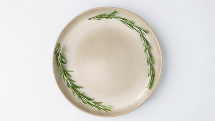 beige plate stands on a gray background close up. wreath of fresh rosemary on a plate. minimalist concept, copy space, space for text 