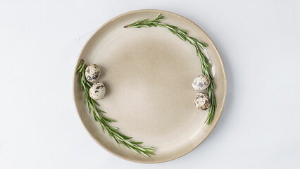 The beige plate stands on a grey close-up background. in the plate lies a wreath of rosemary and...