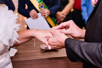 Obraz premium the hands of the bride and groom exchanging rings and in the background people watching