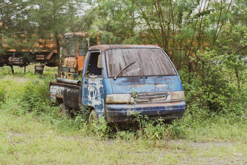 Side view of an abandoned blue pick up vehicle stay strong with a truck in the background