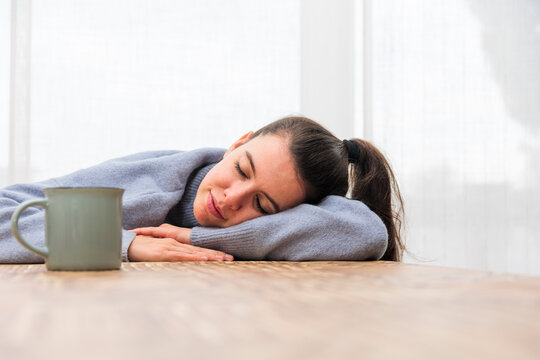 Girl falls asleep at the table with a cup of coffee