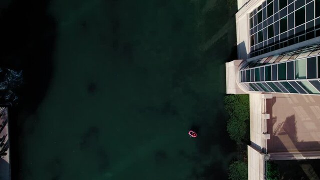 Top down aerial: Person in rubber boat peddling through the Lez in Antigone, Montpellier, France.