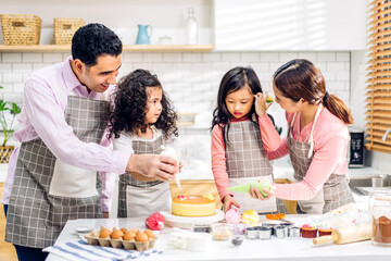 Obraz na płótnie Canvas Portrait of enjoy happy love asian family father and mother with little asian girl daughter child play and having fun cooking food together with baking cookie and cake ingredient in kitchen