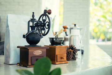 Coffee grinder with coffee beans bag and old coffee mill on the coffee shop bar counter