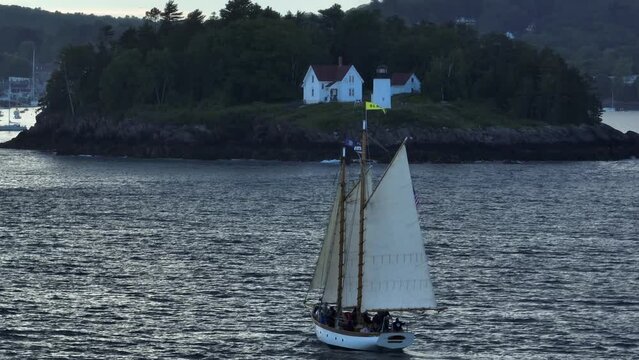 Classic wooden sailboat sails past Curtis Island Lighthouse