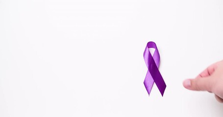 Detail of male hand placing ribbon in purple color over white background. Copy space.
