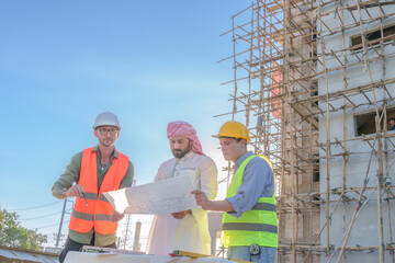 Diverse team of professionals using tablet computers on construction site. Real estate construction project. with civil engineers, architects, Arabic business investors and explorer with theodolite