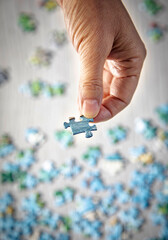 Close up of a hand holding a puzzle piece with others diffused below