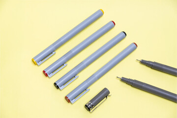 Group of markers and pens cut out on yellow background. Art directed arrangement.