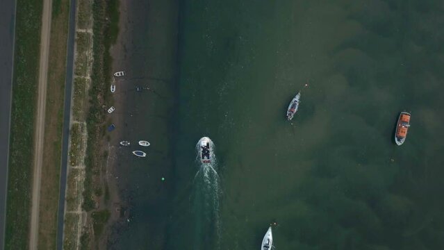 Top Down Drone Shot of Small Working Fishing Boat Travelling Through Creek Harbour with Other Small Sailing Boats on UK East Coast