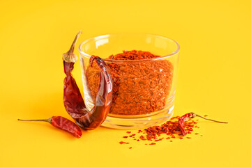 Bowl of chipotle chili flakes on color background