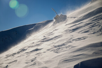 Snow texture. Strong wind in Carpathian mountains in winter on a sunny day. Wind sculpted patterns on snow surface