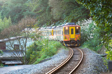 Naklejka premium Diesel yellow train travels in the mountains and forests. Sandiaoling Railway Station, Ruifang District, New Taipei City, Taiwan