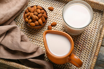 Tray with jug, glass of almond milk and nuts, closeup