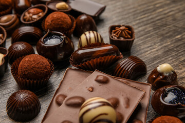 Chocolate bars and candies on wooden background, closeup