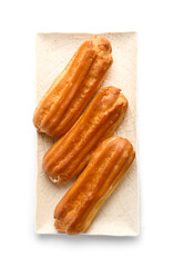Plate with sweet eclairs on white background