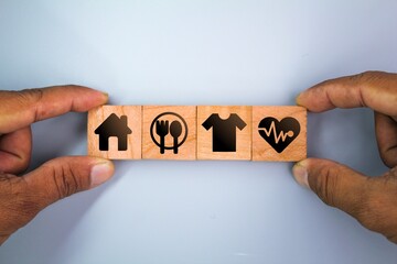 wooden cube with icons of food, Clothing, housing, medicine, four basic human needs concepts. Four Basic Human Material Needs.