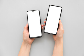 Female hands with modern mobile phones on light background, closeup
