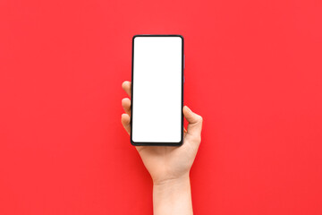 Female hand with modern mobile phone on red background