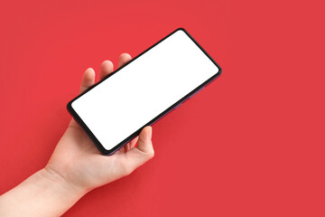 Female hand with modern mobile phone on red background, closeup