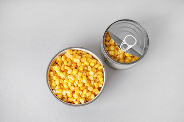 Bowl and tin can with canned corn on grey background