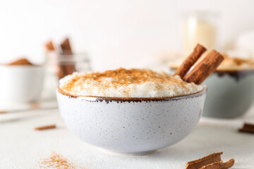 Bowl with delicious rice pudding and cinnamon on white table