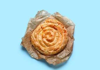 Delicious cheese pie in baking paper on blue background