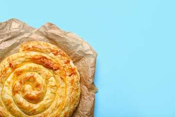 Delicious cheese pie in baking paper on blue background