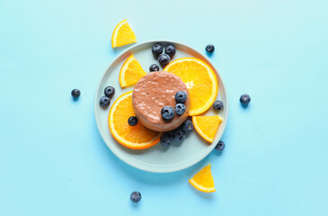 Plate with delicious chocolate pudding, orange slices and blueberry on blue background