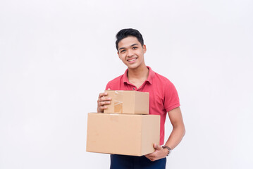 A young man in a red polo shirt holding 2 cardboard boxes. Isolated on a white background.