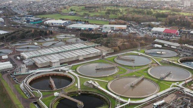 Aerial shot zooms in towards a large sewage processing plant in Edinburgh on a grey day.
