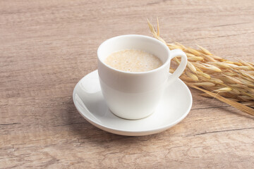 Hot oatmeal in white cup on wooden background