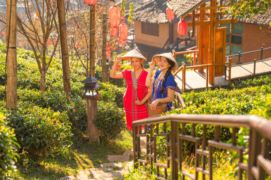 Two of pretty Asian women stand on stair along the way down from hill and posture for taking picture in place of travel landmark in Thailand.